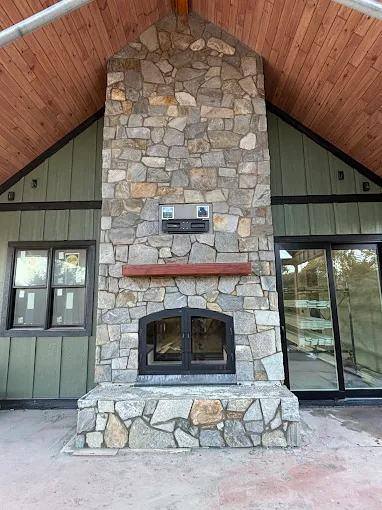 Outdoor stone fireplace under a cedar ceiling